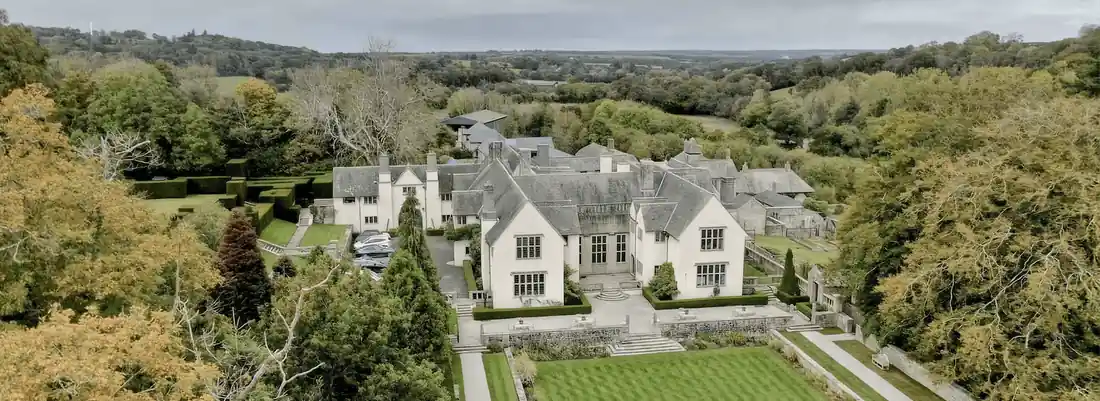 Wood House and its walled gardens from the air, surrounded by Devon woodland